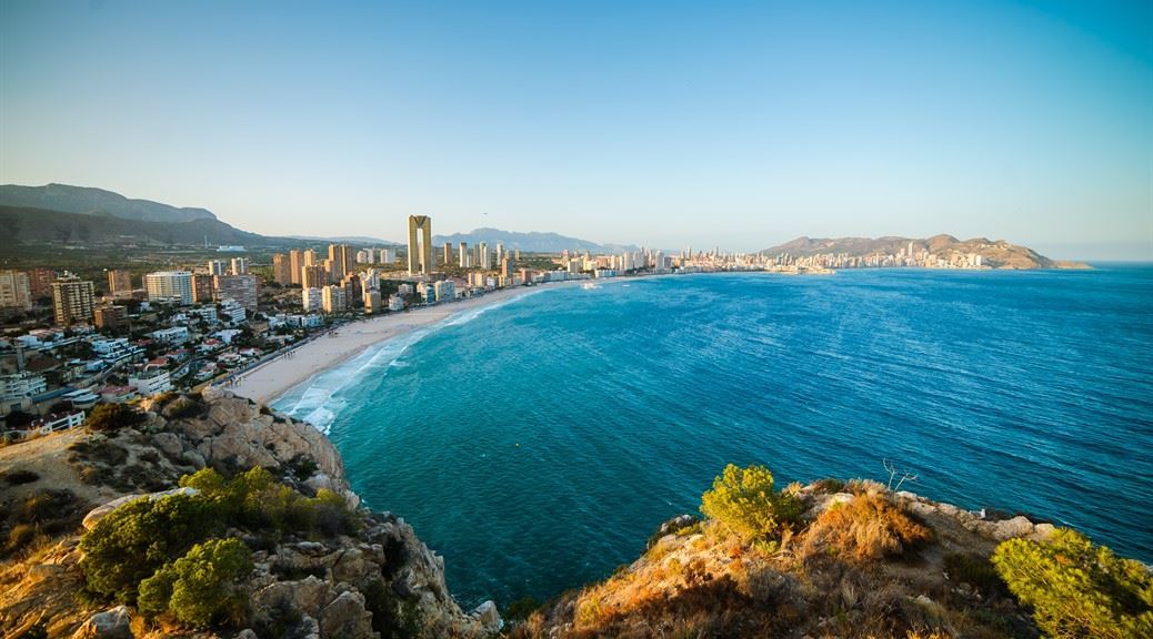 City and beach of Benidorm seen through the rocks on a sunny day